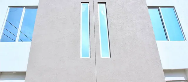 Fachada blanca con ventanas verticales estrechas de composición geométrica