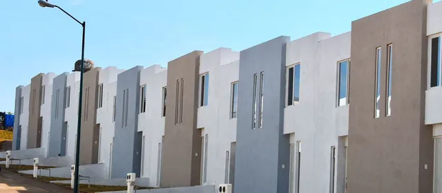 Hilera de viviendas en desarrollo con cancelería repetida en toda la calle