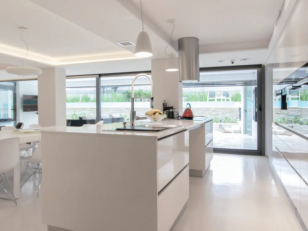 Cocina blanca con ventanales corridos y puerta corrediza de PVC hacia el patio