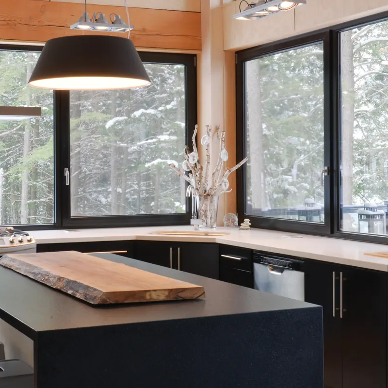 Cocina con isla de madera maciza y ventanales de PVC de piso a techo hacia el bosque