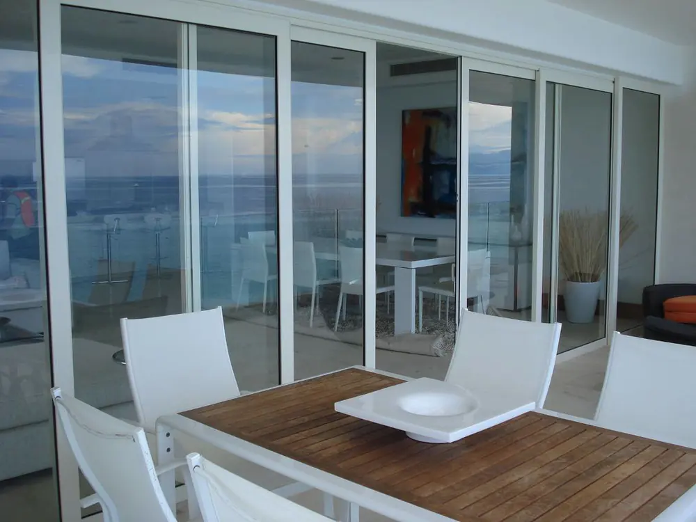 Comedor exterior con cancelería de PVC de piso a techo y vista al lago