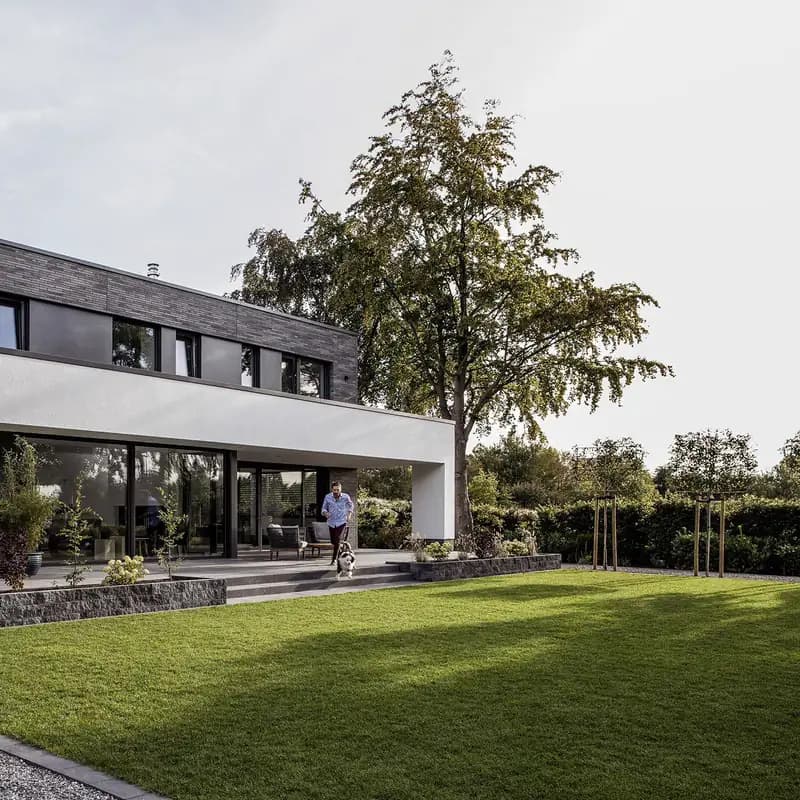 Casa contemporánea de una planta con ventanales corridos, vista desde el jardín