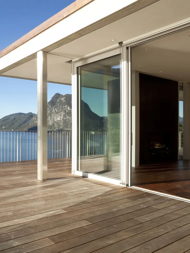 Terraza de madera con puerta corrediza de PVC de gran claro abierta hacia el interior