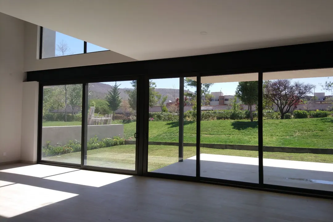 Interior en obra terminada con cancelería corrediza de gran claro hacia el jardín