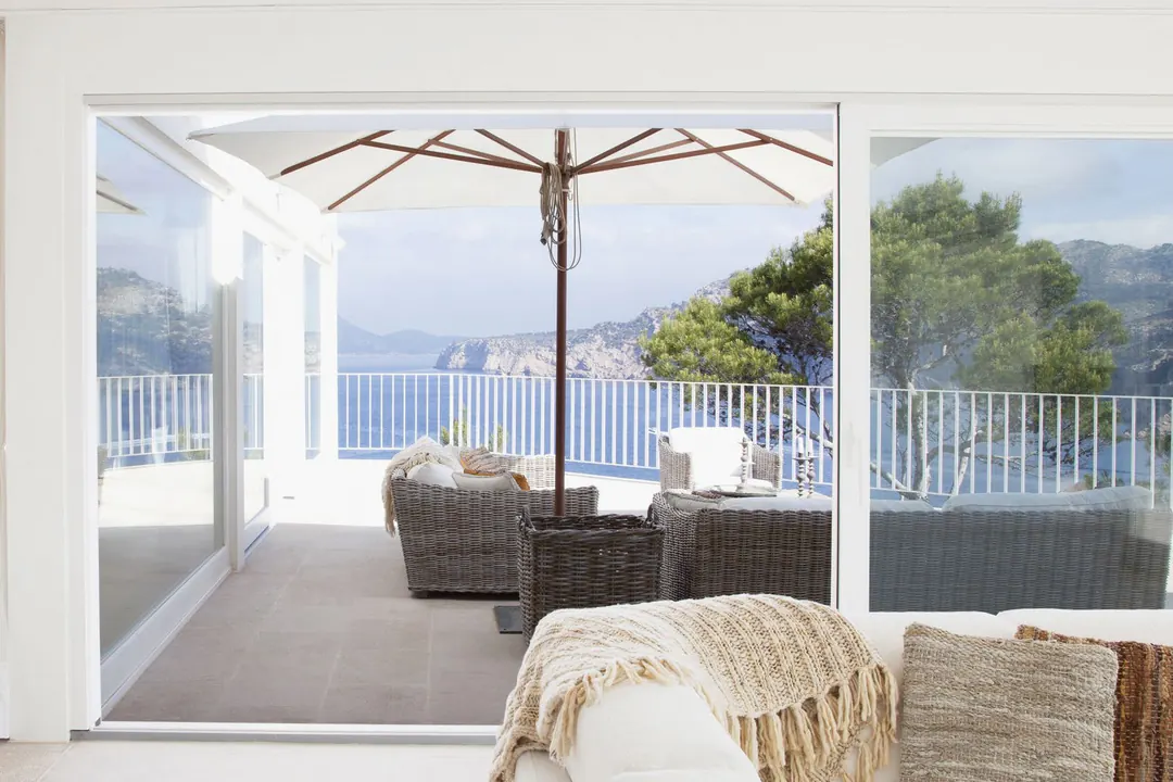 Puerta corrediza de gran formato abierta hacia una terraza con vista al mar