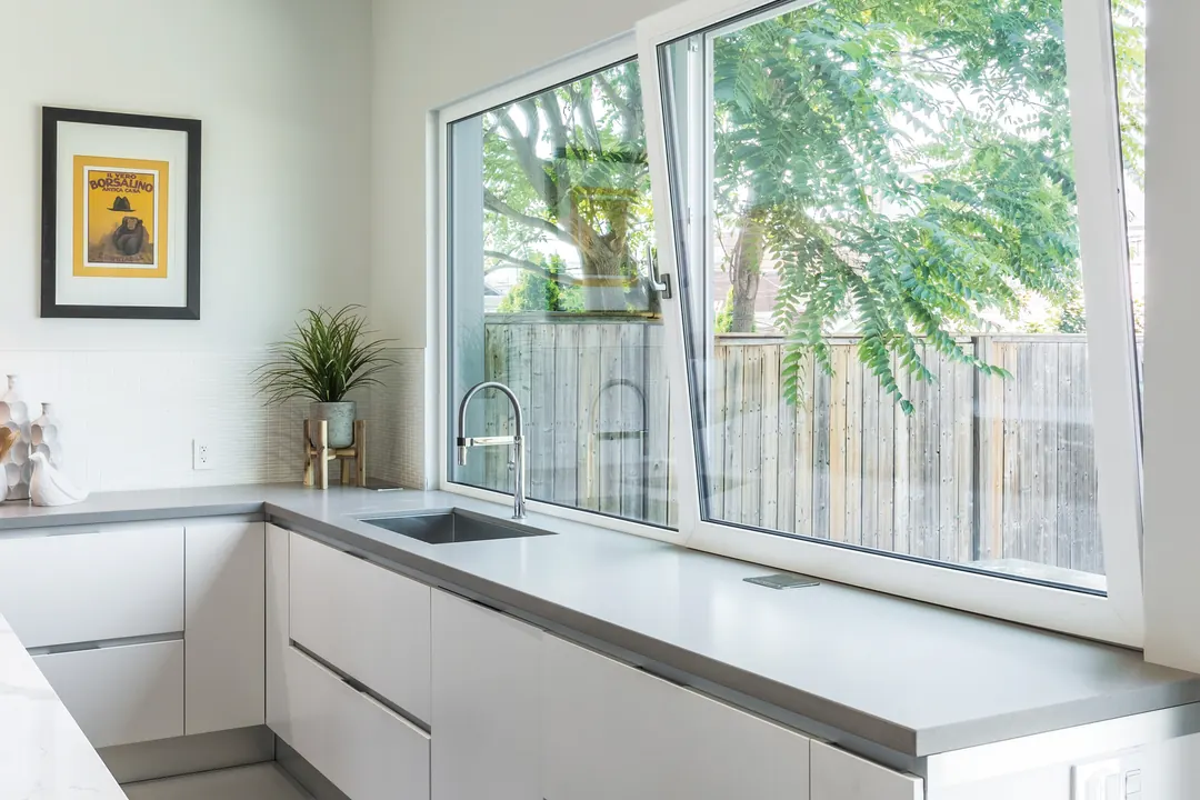 Cocina con ventana corrediza de gran formato abierta sobre la cubierta de trabajo